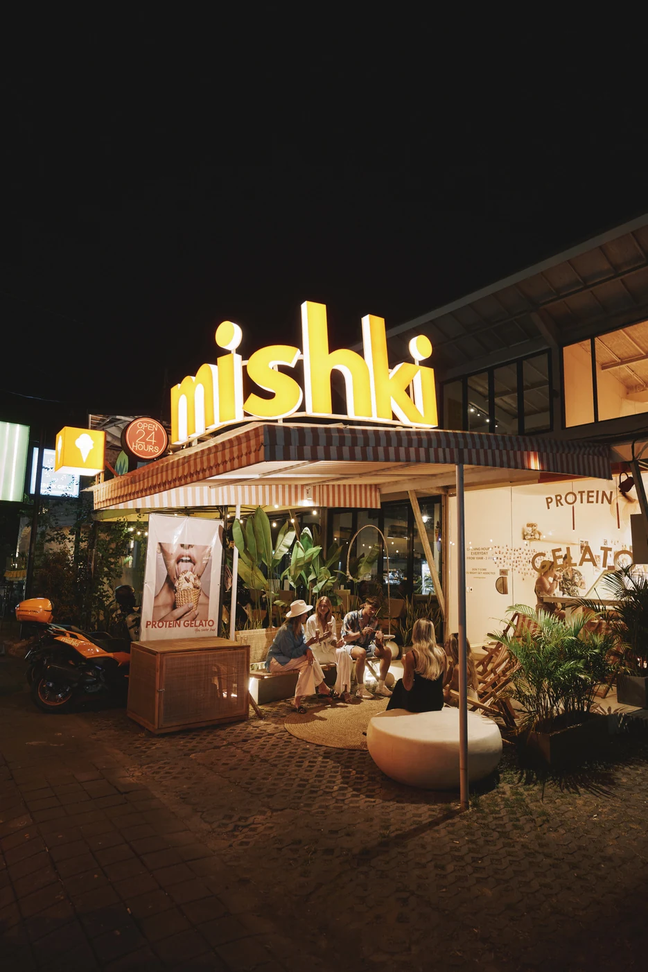 The Mishki boutique facade at night with its glowing sign